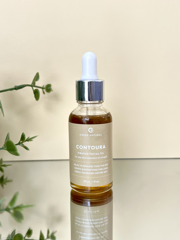Bottle of Contoura facial oil with dropper on a reflective surface with a light background