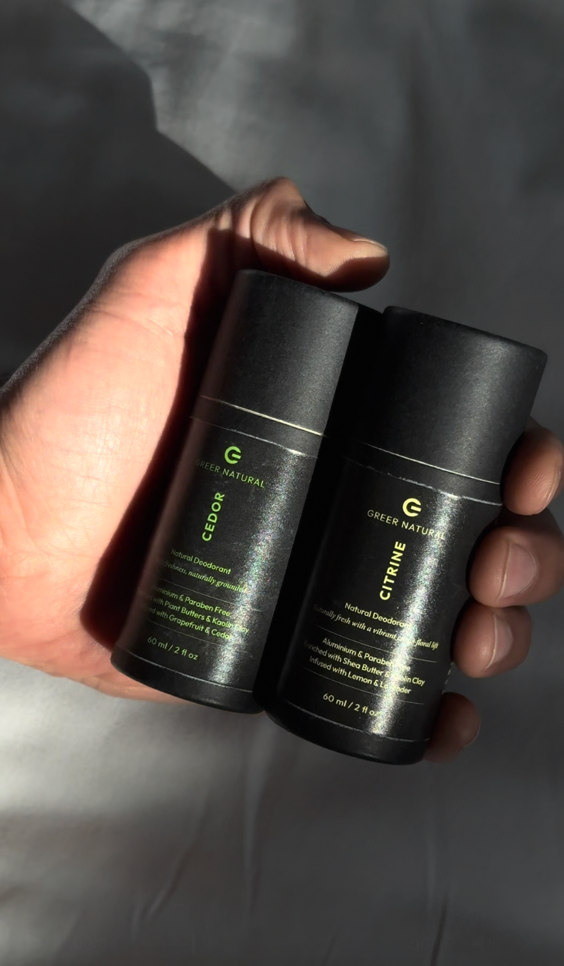 Two black skincare products held in a hand against a neutral background