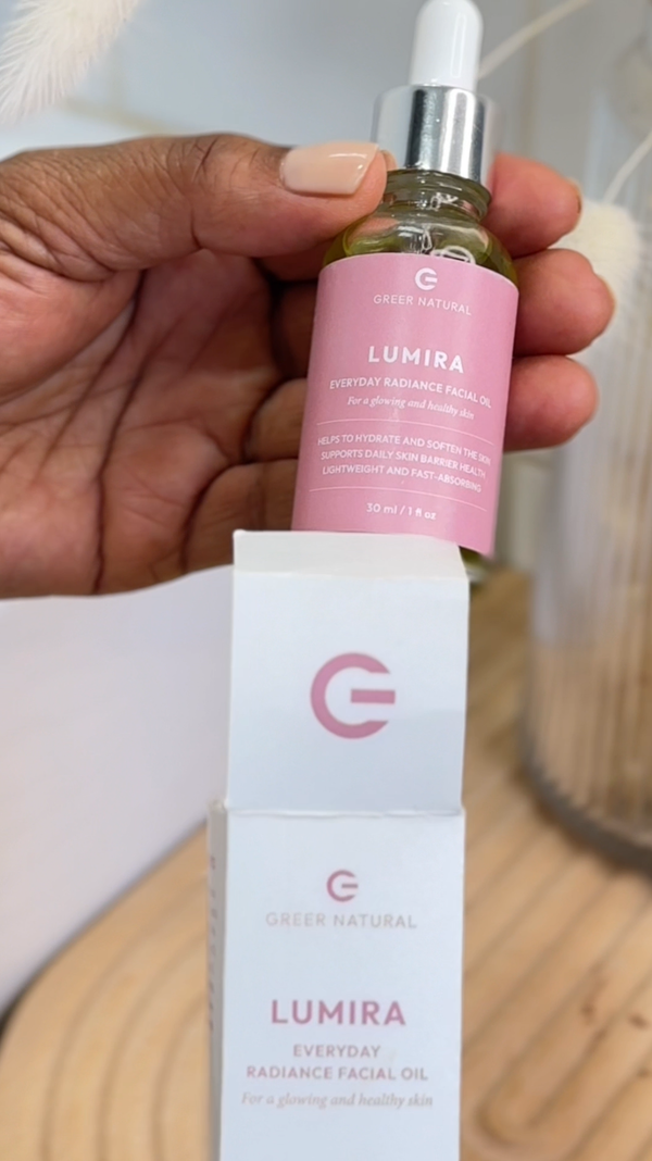 Hand holding a bottle of Lumira facial oil with a visible brand logo.