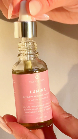 Bottle of Greer Natural Lumira facial oil held by a hand with pink nail polish.