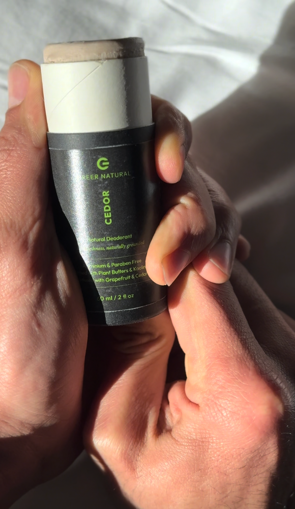 Hand holding a bottle of 'Greer Natural Cedor' deodorant.