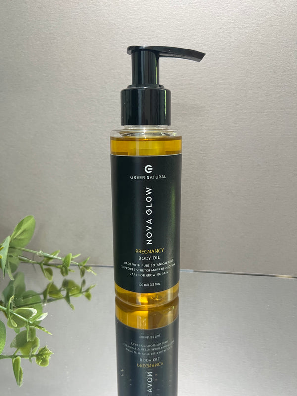 Bottle of Nova Glow pregnancy body oil on a metallic surface with a plant in the corner.