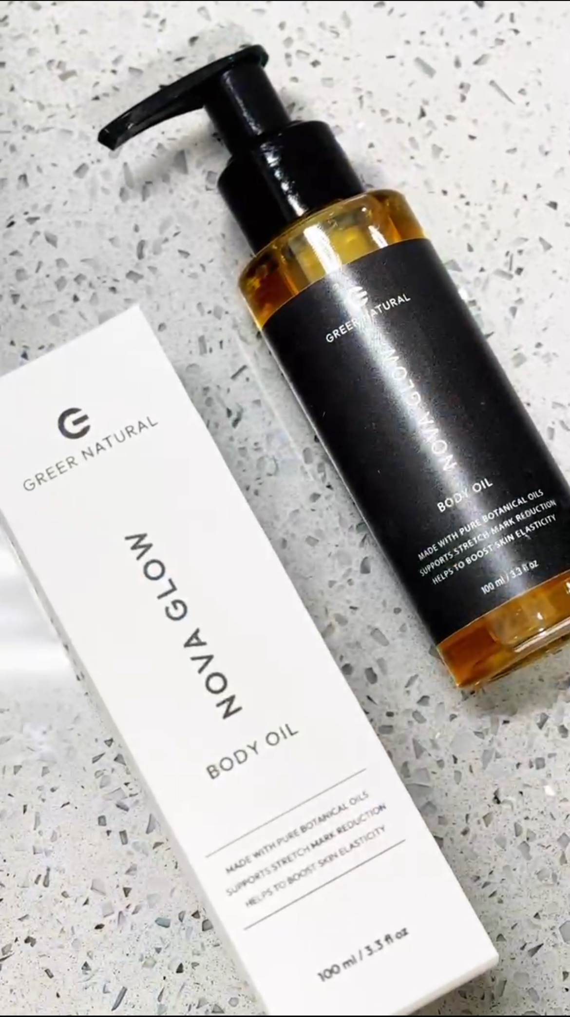 Body oil bottle and its packaging on a textured surface