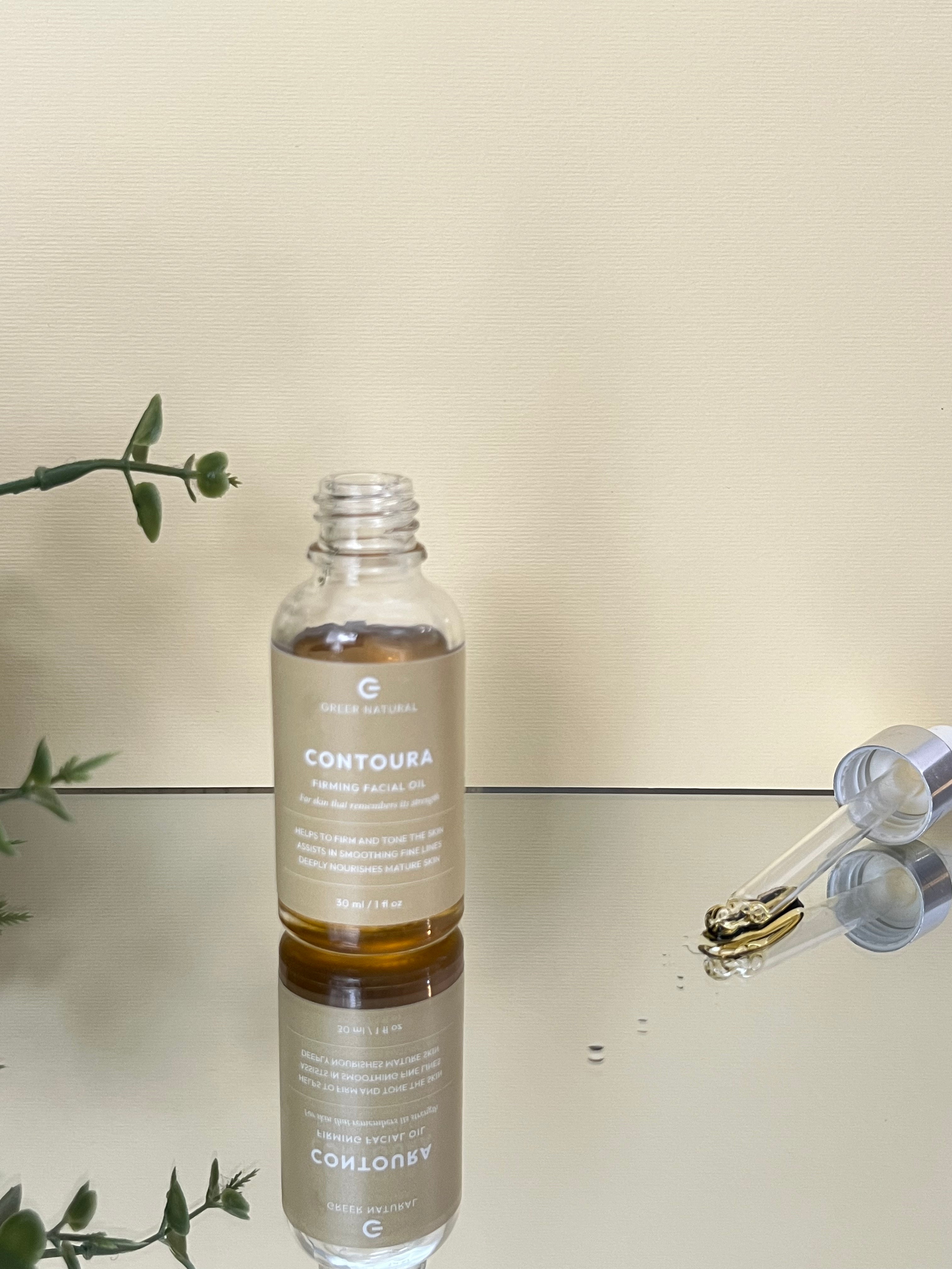 Bottle of Contoura skincare product with dropper on a reflective surface.